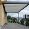 Bioklimatinė pergola praviru stogu namo kieme ant trinkelių