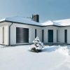 Baltas namas ziema su tamsiomis apsauginemis zaliuzemis