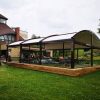 Tamsi tradicinė tentinė pergola riestu stogu prie pastato